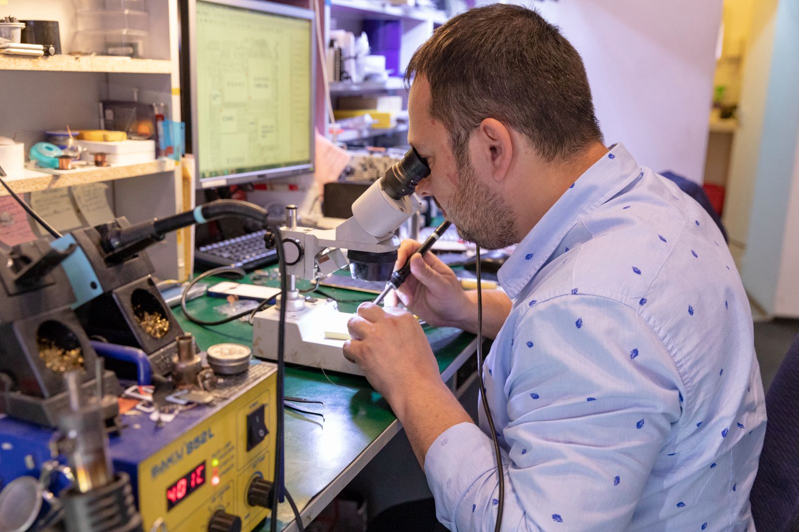Lucru pe placa unui telefon, la microscop, în service-ul iFIX ALL